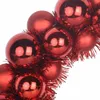 A close-up view of red Christmas ornaments intertwined with tinsel. Produktbild-Vorschau