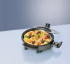 A close-up shot of an electric multi-function pan filled with paella, placed on a light blue surface with a gradient blue background. Produktbild-Vorschau