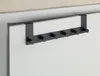 A black over-the-door hook rack is mounted on the top edge of a white door. Podgląd zdjęcia produktu