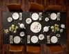 A formal table setting for a tea or meal, with plates, cups, teapots, and floral decorations. Produktbild-Vorschau