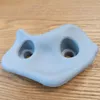 A light blue climbing hold is placed on a wooden surface. Voir les images du produit