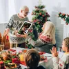 A family is gathered around a Christmas tree and a dinner table, looking at a digital photo frame. Produktbild-Vorschau