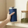 Blauer elektrischer Mühle mit durchsichtigem Deckel und goldenem Akzent, gehalten von einer Hand neben einem Glas mit Bohnen auf einem Regal Náhľad obrázku produktu