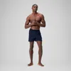 A man wearing navy blue swim shorts stands against a light gray background. Produktbild-Vorschau