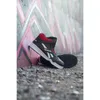 A pair of black and red high-top Reebok sneakers leaning against a graffiti-covered wall. Náhľad obrázku produktu