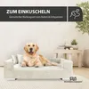 A golden retriever dog is lying on a beige dog sofa in a living room setting. Voir les images du produit