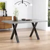 A dining table with a concrete-look top and black X-shaped legs, set in a modern dining room. Produktbild-Vorschau