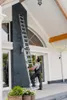 A person is using a ladder to reach a high part of a house exterior. Produktbild-Vorschau