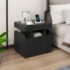A black nightstand next to a bed, with a phone charging on top. Podgląd zdjęcia produktu