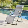 A lounge chair is placed on a patio next to a swimming pool. Produktbild-Vorschau