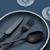 A close-up shot of black cutlery on a dark blue plate. Podgląd zdjęcia produktu
