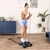 A woman is exercising on a stepper machine with resistance bands in a living room. Voir les images du produit