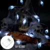 Halloween-themed decoration with ghost lights, skulls, and fake spider web. Produktbild-Vorschau