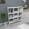 A white cube shelf unit filled with decorative items and books, placed in a room with gray walls and a light gray floor. Produktbild-Vorschau