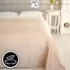 A neatly made bed with a beige striped blanket and white pillows, next to a small white side table with a vase of flowers. Anteprima dell’immagine prodotto