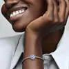 A close-up shot of a woman's arm wearing a Pandora bracelet with a blue flower charm. Anteprima dell’immagine prodotto