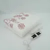 A folded electric blanket with a rose pattern and a controller on a white background. Produktbild-Vorschau