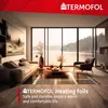 A living room with a large window overlooking a lake, featuring a sofa, armchair, and coffee table. Produktbild-Vorschau