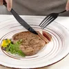 A close-up of a person cutting a steak on a plate with a knife and fork. Produktbild-Vorschau