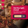 People gathered around a table for a meal, with decorative lights in the background. A pink overlay highlights smart lighting features. Produktbild-Vorschau