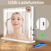 A woman is applying makeup in front of a lighted mirror, with a phone charging from the mirror's USB port. Anteprima dell’immagine prodotto