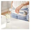 A person is pouring water from a bottle into a glass. Produktbild-Vorschau