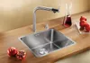 A modern kitchen sink setup with a faucet, sink, and decorative elements like pomegranates and a carafe of red liquid. Produktbild-Vorschau
