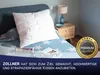 A pillow on a bed with a nightstand and lamp in the background. Produktbild-Vorschau