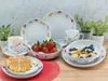 A table setting with a floral patterned dinnerware set, including plates, bowls, and a mug, along with a waffle, strawberries, and blueberries. Náhľad obrázku produktu