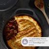 A close-up of a pot pie in a cast iron pot, with a wooden spoon in the background. Produktbild-Vorschau