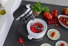 A KitchenAid stand mixer with an ice cream maker attachment is shown, surrounded by fresh tomatoes and basil, suggesting a culinary preparation. Produktbild-Vorschau