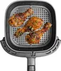 Three cooked chicken drumsticks are arranged on a perforated metal rack inside an air fryer basket. Produktbild-Vorschau