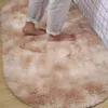 Hellbrauner ovaler flauschiger Teppich auf Holzboden, nackte Füße einer Person treten vom Bett darauf Anteprima dell’immagine prodotto
