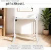 A white adjustable desk frame in a modern interior setting with a bookshelf and a plant. Náhled obrázku produktu
