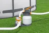 A sand filter and pump system connected to an above-ground swimming pool, situated on a grassy lawn. Produktbild-Vorschau