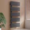 A modern anthracite radiator is mounted on a brown wall next to a large green plant and a shower enclosure. Podgląd zdjęcia produktu