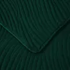 A close-up view of a dark green quilted blanket or throw with a wave-like pattern. Podgląd zdjęcia produktu