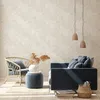 A cozy living room scene with a rattan chair, a blue ottoman, and a dark blue sofa with pillows, set against a textured beige wall. Podgląd zdjęcia produktu