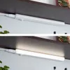 Two images showing an LED under-cabinet light strip mounted under a shelf. The top image shows the light strip off, and the bottom image shows it illuminated. Náhľad obrázku produktu