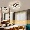 A hand holding a smartphone showing a ceiling light, with the actual ceiling light visible in the background above a bedroom. Voir les images du produit