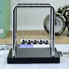 A close-up shot of a Newton's cradle on a desk with books and a clock in the background. Produktbild-Vorschau