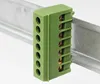 A green terminal block is mounted on a silver DIN rail. Produktbild-Vorschau