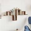 A wooden wall shelf with decorative items and books, mounted on a white wall next to a blue armchair. Produktbild-Vorschau