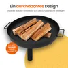 A black metal fire pit filled with firewood, placed on a yellow patterned surface. Produktbild-Vorschau