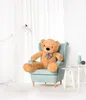 A large teddy bear sits in a light blue armchair in a brightly lit room with white curtains. Náhľad obrázku produktu