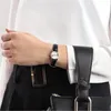 A woman's wrist wearing a watch, with a black handbag strap visible. Anteprima dell’immagine prodotto