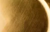 A close-up of a textured gold surface, likely a decorative plate, showing brushed metal details and a curved highlight. Produktbild-Vorschau