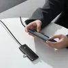 A person is using a smartphone connected to a USB hub. Voir les images du produit