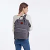 A woman wearing a white sweater and blue jeans is carrying a gray backpack. Produktbild-Vorschau