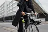 A person riding a bicycle in an urban environment, holding a portable blender. Voir les images du produit